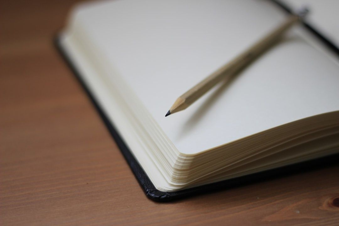 Open blank notebook with a wooden pencil on a wooden desk